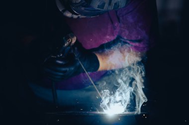 Etrafındaki kıvılcımlar uçuşurken tamirci atölyesinde kaynak ve öğütme yapıyordu. Koruyucu kask ve ekipman takıyor..