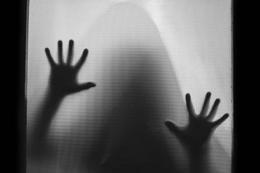 Horror ghost figure behind the matte glass. Halloween festival concept.