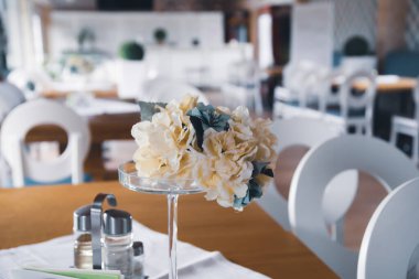 Konforlu, modern bir restoranın masasında çiçek süslemesi..