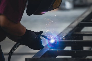 Handyman performing welding and grinding at his workplace in the workshop, while the sparks 