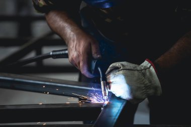 Handyman performing welding and grinding at his workplace in the workshop, while the sparks 