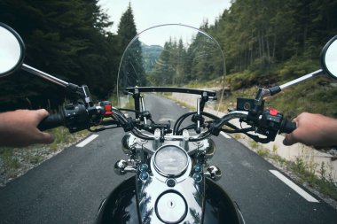 Orman yolunda giden motosikletli bir sürücünün ellerinde. Seyahat ve spor, hız ve özgürlük kavramı
