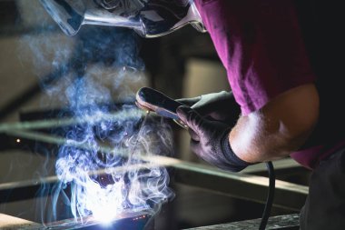 Handyman performing welding and grinding at his workplace in the workshop, while the sparks 