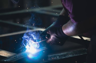 Etrafındaki kıvılcımlar uçuşurken tamirci atölyesinde kaynak ve öğütme yapıyordu. Koruyucu kask ve ekipman takıyor..