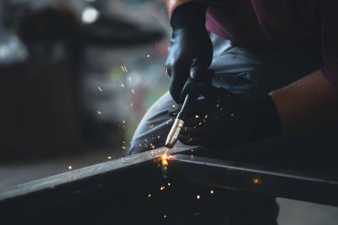 Etrafındaki kıvılcımlar uçuşurken tamirci atölyesinde kaynak ve öğütme yapıyordu. Koruyucu kask ve ekipman takıyor..