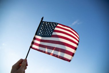 Hand holding American flag. National symbol of the United States of America.