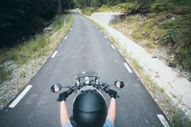 Biker girl on a motorcycle on summer forest road. Travel and sport, speed and freedom concept.