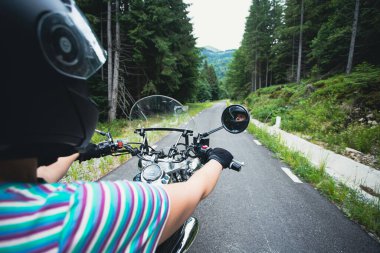 Yaz ormanı yolunda motorsikletli bir kız. Seyahat ve spor, hız ve özgürlük kavramı.