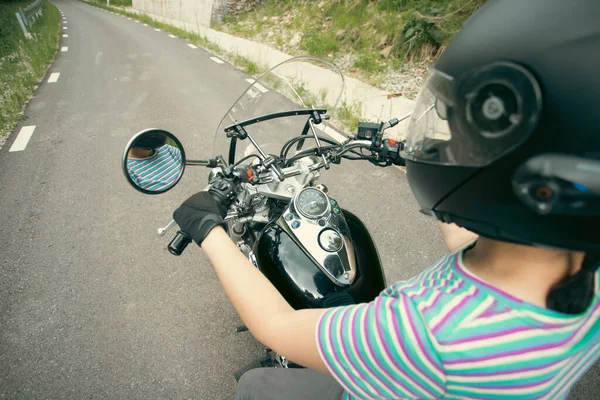 Biker girl on a motorcycle on summer forest road. Travel and sport, speed and freedom concept.