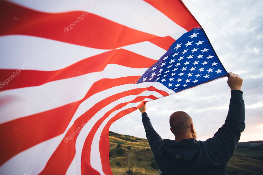Man holding american USA flag in the sunset. Independence Day or traveling in America concept.