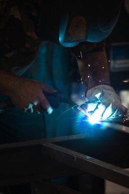 Etrafındaki kıvılcımlar uçuşurken tamirci atölyesinde kaynak ve öğütme yapıyordu. Koruyucu kask ve ekipman takıyor..