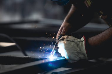 Handyman performing welding and grinding at his workplace in the workshop, while the sparks 