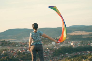 Elinde Gay Gökkuşağı Bayrağı olan bir kadın. Aynı cinsiyet çiftleri için mutluluk, özgürlük ve aşk kavramı