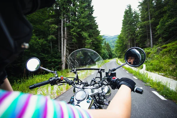 Yaz ormanı yolunda motorsikletli bir kız. Seyahat ve spor, hız ve özgürlük kavramı.