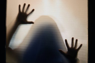 Horror ghost figure behind the matte glass. Halloween festival concept.