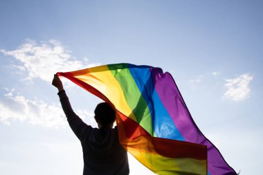 Woman holding a Gay Rainbow Flag. Happiness, freedom and love concept for same sex couples