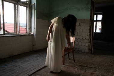 Ghost in abandoned, haunted house. Horror scene of scary spirit of a woman, halloween concept.