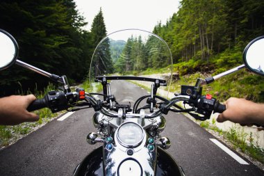 Orman yolunda giden motosikletli bir sürücünün ellerinde. Seyahat ve spor, hız ve özgürlük kavramı