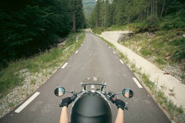 Yaz ormanı yolunda motorsikletli bir kız. Seyahat ve spor, hız ve özgürlük kavramı.