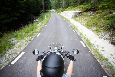 Biker girl on a motorcycle on summer forest road. Travel and sport, speed and freedom concept.