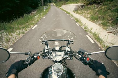 Orman yolunda giden motosikletli bir sürücünün ellerinde. Seyahat ve spor, hız ve özgürlük kavramı