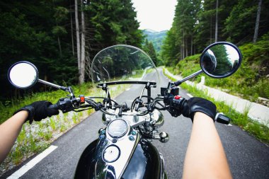 Orman yolunda giden motosikletli bir sürücünün ellerinde. Seyahat ve spor, hız ve özgürlük kavramı