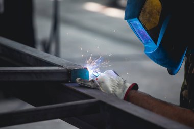 Handyman performing welding and grinding at his workplace in the workshop, while the sparks 