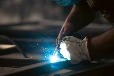 Handyman performing welding and grinding at his workplace in the workshop, while the sparks 