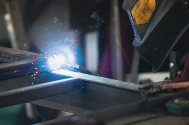 Etrafındaki kıvılcımlar uçuşurken tamirci atölyesinde kaynak ve öğütme yapıyordu. Koruyucu kask ve ekipman takıyor..