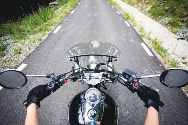 Orman yolunda giden motosikletli bir sürücünün ellerinde. Seyahat ve spor, hız ve özgürlük kavramı