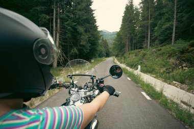 Biker girl on a motorcycle on summer forest road. Travel and sport, speed and freedom concept.