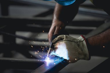 Handyman performing welding and grinding at his workplace in the workshop, while the sparks 