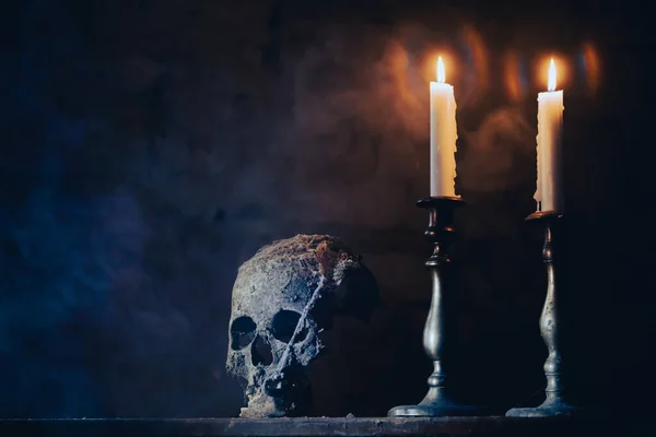 Real human skull with candles in the darkness. Spooky, horror wallpaper for Halloween.