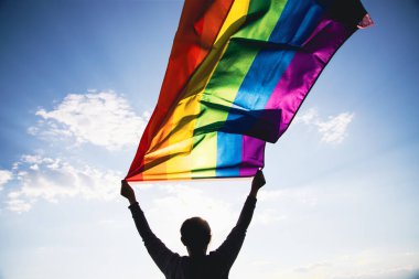 Woman holding a Gay Rainbow Flag. Happiness, freedom and love concept for same sex couples