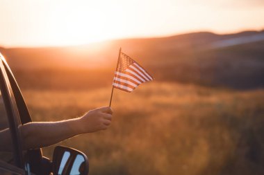 Man holding an American flag on a road trip. Independence Day or traveling in America concept.