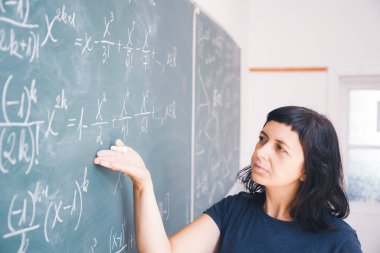 Okulda matematik dersi sırasında tahtaya yazı yazan öğretmen ya da öğrenci..