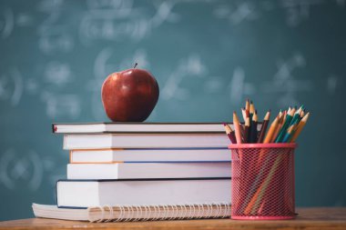 Okul Konseptine geri dönelim. Elma, aksesuarlar ve karatahtaya karşı kitaplar.