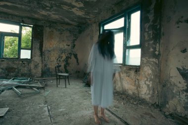 Ghost in abandoned, haunted house. Horror scene of scary spirit of a woman, halloween concept.