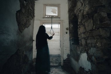 Ghost in abandoned, haunted house. Horror scene of scary spirit of a woman and rope with a noose, halloween concept.