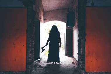 Terk edilmiş, perili bir evde hayalet. Eski balta ve cadılar bayramı konseptini tutan ürkütücü siluet sahnesi.