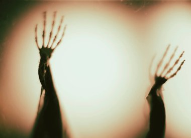 Horror skeleton or grim reaper behind the matte glass. Halloween festival concept.Blurred picture