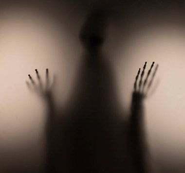 Horror skeleton or grim reaper behind the matte glass. Halloween festival concept.Blurred picture