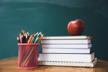 Okul Konseptine geri dönelim. Elma, aksesuarlar ve karatahtaya karşı kitaplar.