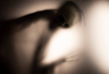 Horror skeleton or grim reaper behind the matte glass. Halloween festival concept.Blurred picture