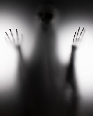 Horror skeleton or grim reaper behind the matte glass. Halloween festival concept.Blurred picture