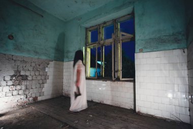 Terk edilmiş, perili bir evde hayalet. Korku sahnesi. Elinde balta, cadılar bayramı konsepti olan ürkütücü siluet..