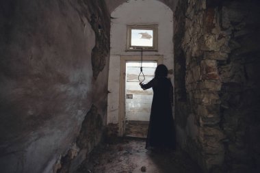 Ghost in abandoned, haunted house. Horror scene of scary spirit of a woman and rope with a noose, halloween concept.