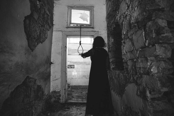 Ghost in abandoned, haunted house. Horror scene of scary spirit of a woman and rope with a noose, halloween concept.