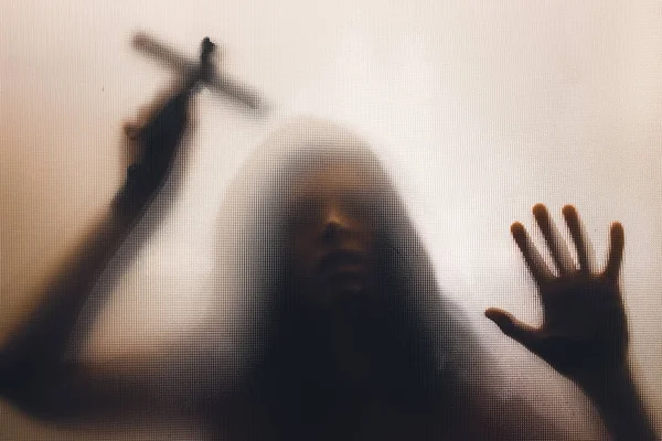 Τρομακτική Γυναίκα Φάντασμα Κρατώντας Ένα Σταυρό Πίσω Από Ματ Γυαλί — Φωτογραφία Αρχείου