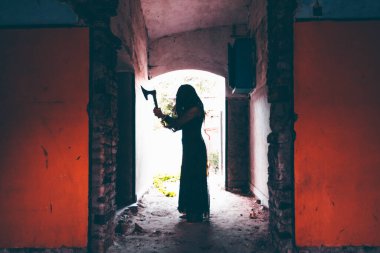 Ghost in abandoned, haunted house. Horror scene of spooky silhouette holding old axe, halloween concept.